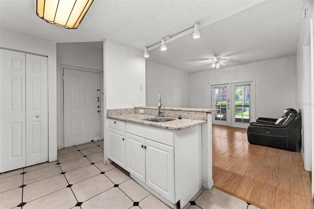 kitchen with a textured ceiling, white cabinets, track lighting, sink, and ceiling fan