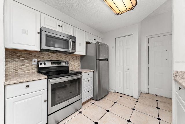 kitchen featuring white cabinets, a textured ceiling, decorative backsplash, and appliances with stainless steel finishes