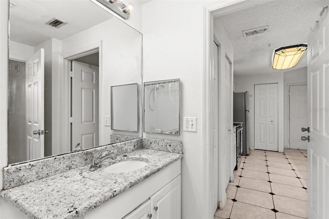 bathroom with a textured ceiling, tile patterned floors, and vanity