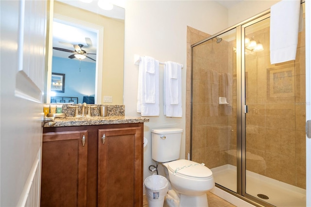 bathroom with ceiling fan, vanity, toilet, and a shower with door