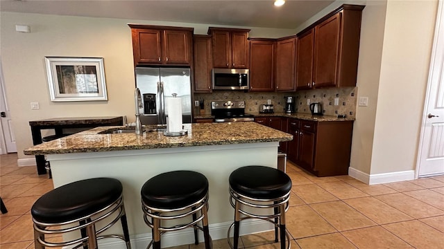 kitchen with sink, light tile patterned floors, a breakfast bar, stainless steel appliances, and tasteful backsplash