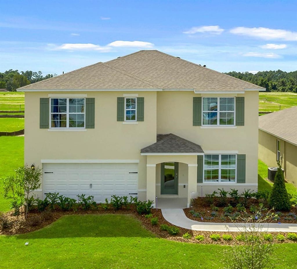 view of front of house with cooling unit, a garage, and a front lawn