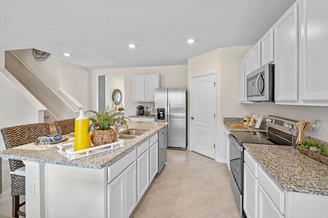 kitchen with white cabinets, a breakfast bar, an island with sink, and stainless steel appliances