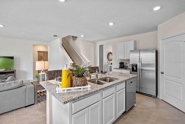 kitchen with white cabinetry, sink, light stone counters, a center island with sink, and appliances with stainless steel finishes