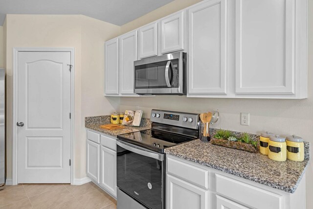 kitchen featuring white cabinets, light tile patterned floors, stainless steel appliances, and light stone countertops