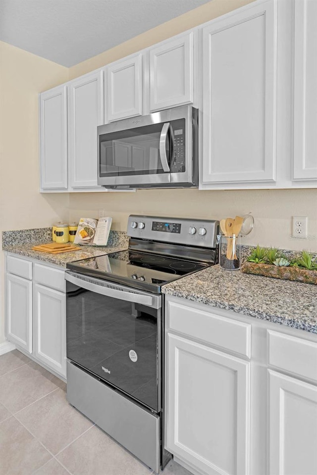 kitchen featuring light tile patterned flooring, light stone counters, white cabinetry, and stainless steel appliances