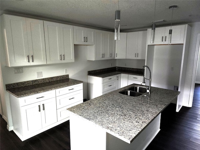 kitchen with sink, a kitchen island with sink, and hanging light fixtures