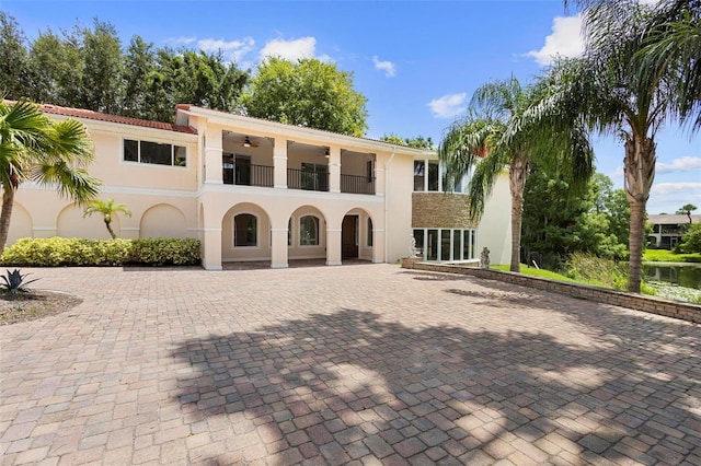 view of front of house with ceiling fan and a balcony