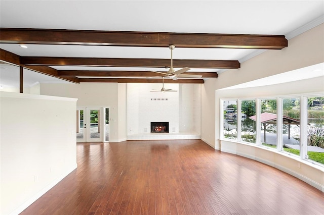 unfurnished living room with ceiling fan, french doors, hardwood / wood-style flooring, beam ceiling, and a fireplace