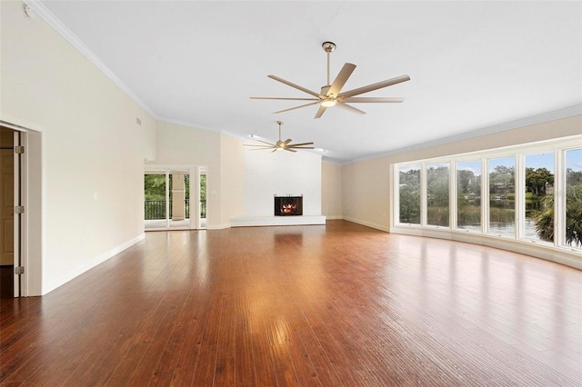 unfurnished living room featuring ceiling fan, hardwood / wood-style flooring, a water view, and a brick fireplace