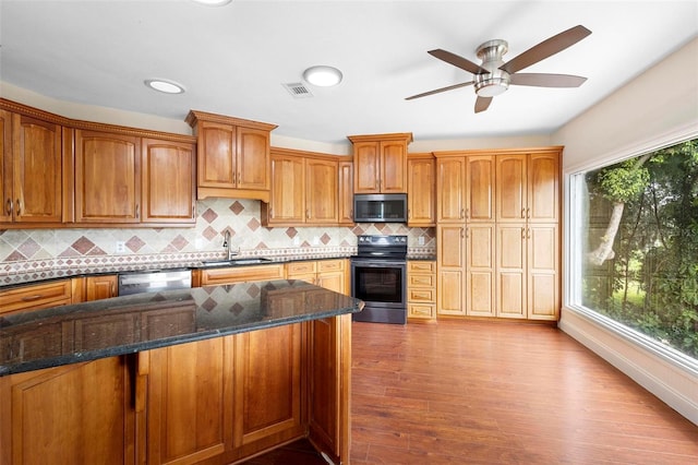 kitchen featuring light hardwood / wood-style floors, sink, stainless steel appliances, and dark stone counters