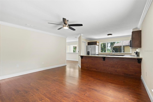 kitchen featuring a kitchen bar, crown molding, stainless steel fridge with ice dispenser, kitchen peninsula, and dark wood-type flooring