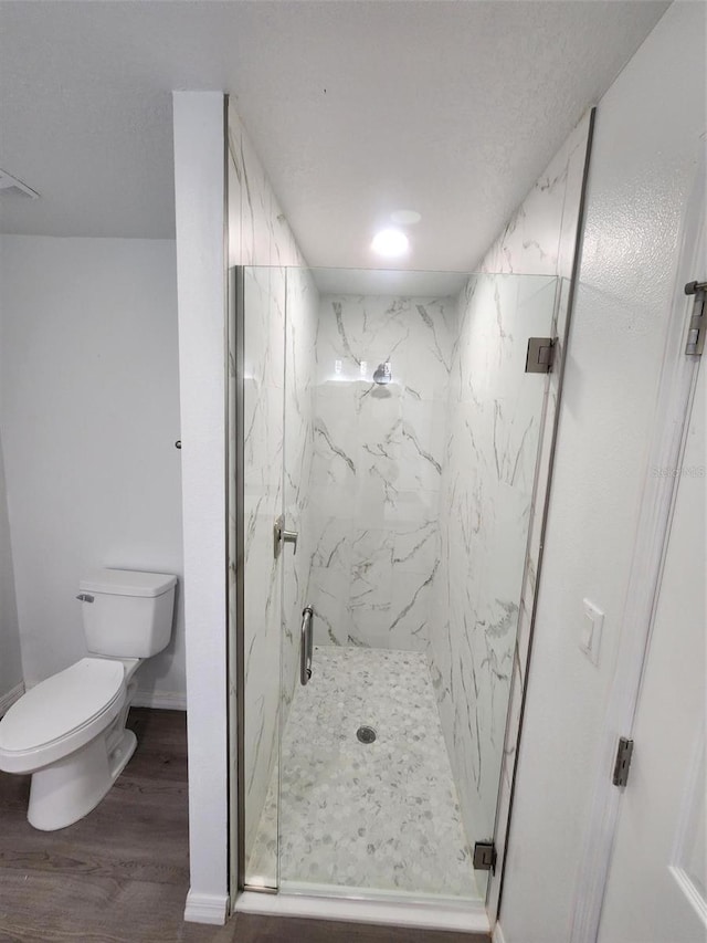 bathroom with wood-type flooring, toilet, and a shower with shower door