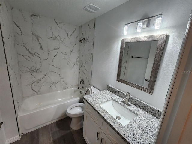 full bathroom with toilet, tiled shower / bath, vanity, a textured ceiling, and hardwood / wood-style flooring