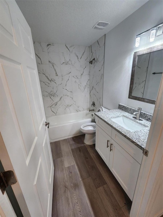 full bathroom with shower / washtub combination, hardwood / wood-style floors, toilet, vanity, and a textured ceiling