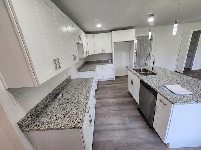 kitchen with a kitchen island with sink, hardwood / wood-style floors, white cabinetry, sink, and light stone countertops