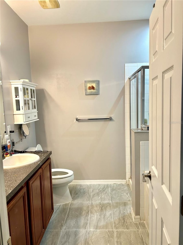 bathroom with tile patterned floors, vanity, a shower with shower door, and toilet