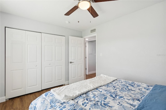 bedroom featuring dark hardwood / wood-style flooring, ceiling fan, and a closet