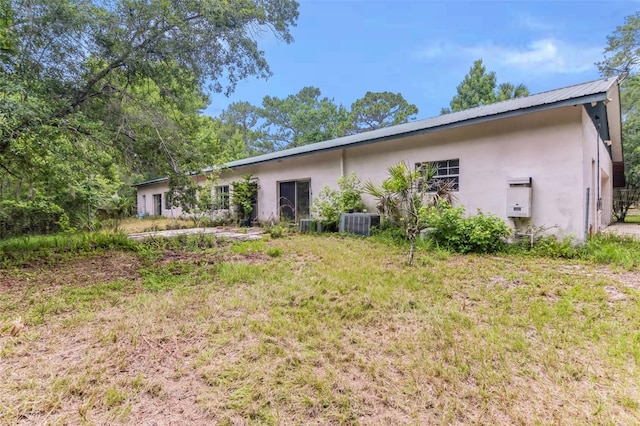 rear view of property with cooling unit and a lawn