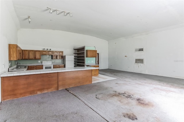 kitchen with lofted ceiling, sink, tile countertops, kitchen peninsula, and white appliances