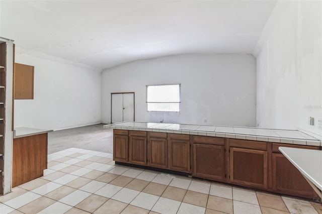 kitchen with tile countertops, kitchen peninsula, and vaulted ceiling