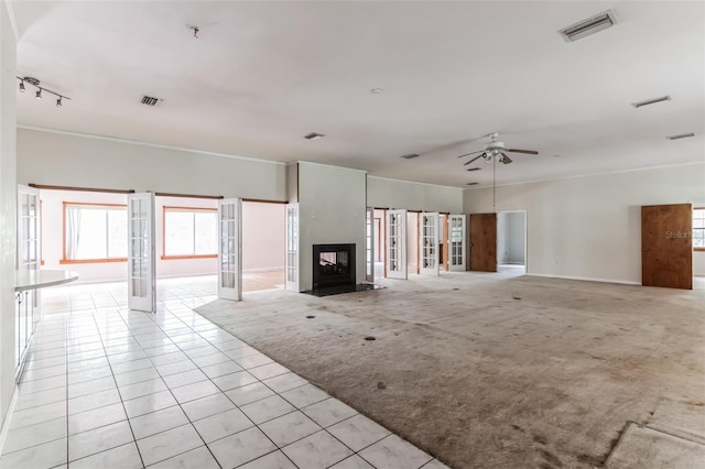 unfurnished living room with light carpet, french doors, ceiling fan, and a multi sided fireplace