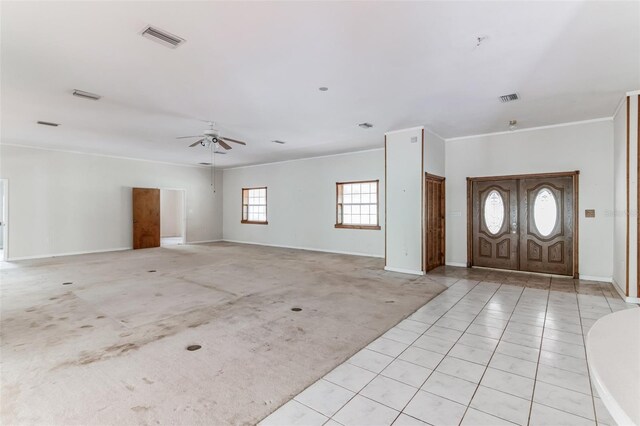 entrance foyer with ceiling fan, ornamental molding, and light carpet