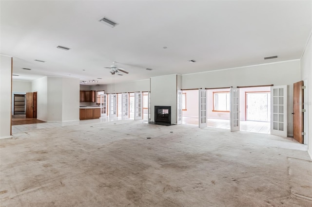 unfurnished living room with crown molding, light carpet, ceiling fan, and french doors