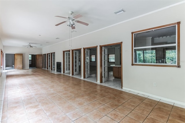 spare room featuring ceiling fan, ornamental molding, and light tile patterned floors