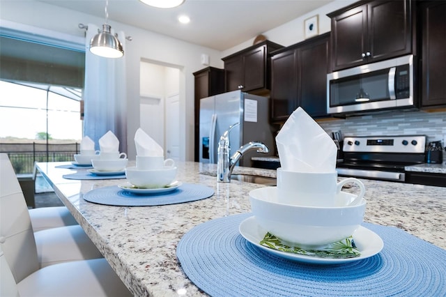 kitchen featuring sink, hanging light fixtures, dark brown cabinets, stainless steel appliances, and tasteful backsplash