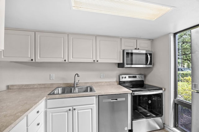 kitchen featuring appliances with stainless steel finishes, white cabinets, and sink