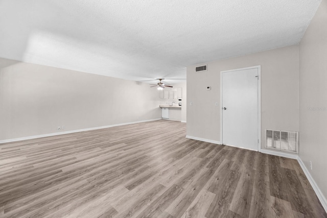 unfurnished living room featuring ceiling fan, a textured ceiling, and light hardwood / wood-style flooring