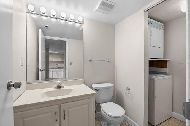 bathroom with toilet, vanity, and stacked washer and clothes dryer