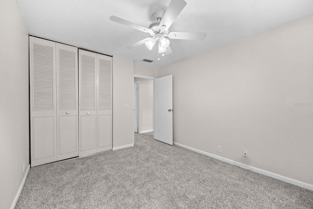 unfurnished bedroom featuring ceiling fan, a closet, and light colored carpet