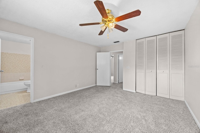 unfurnished bedroom with ceiling fan, connected bathroom, a closet, and carpet flooring