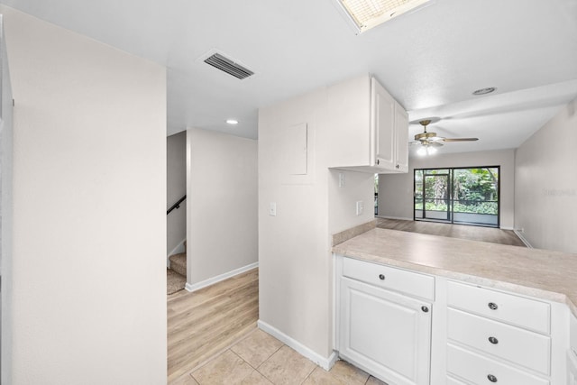 kitchen with ceiling fan, white cabinets, kitchen peninsula, and light tile patterned flooring