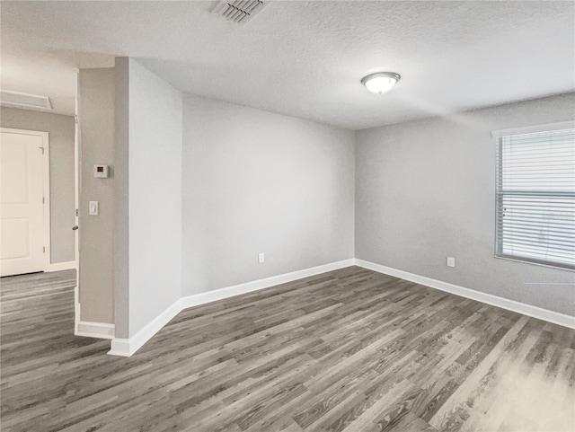 spare room with a textured ceiling and dark wood-type flooring