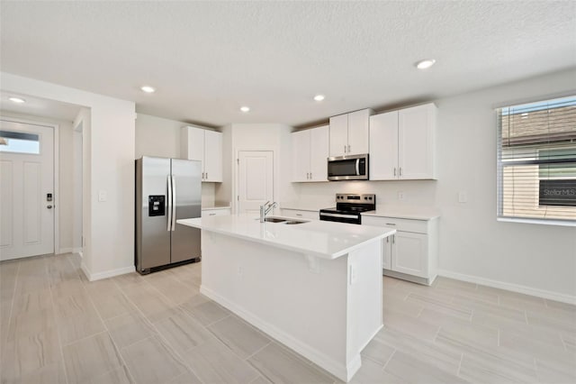 kitchen with appliances with stainless steel finishes, an island with sink, a textured ceiling, white cabinetry, and sink