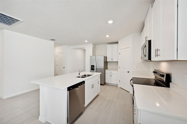 kitchen featuring a textured ceiling, stainless steel appliances, a kitchen island with sink, white cabinets, and sink