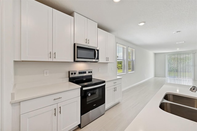 kitchen featuring stainless steel appliances, white cabinets, a textured ceiling, and sink