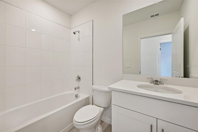 full bathroom featuring vanity, hardwood / wood-style flooring, tiled shower / bath combo, and toilet