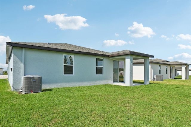 rear view of property with central air condition unit and a yard