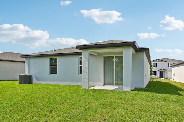 back of house with central air condition unit and a yard