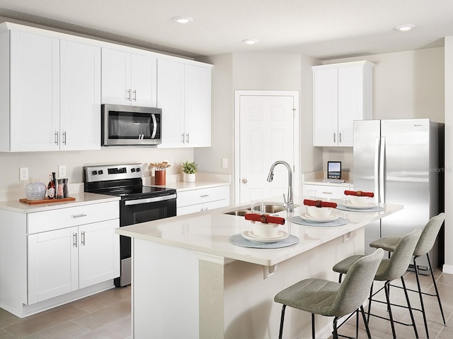 kitchen with sink, white cabinets, stainless steel appliances, and an island with sink