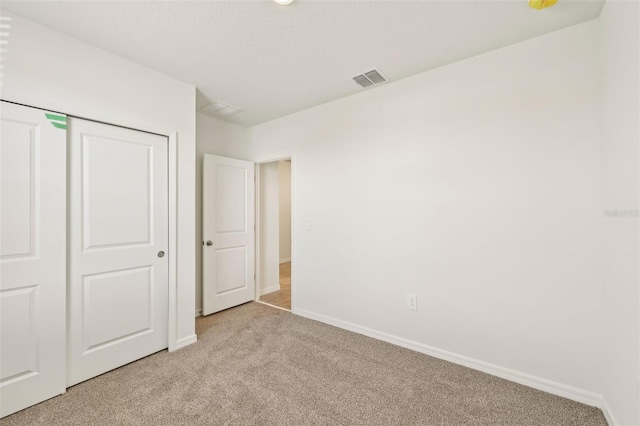 unfurnished bedroom featuring a closet and light carpet