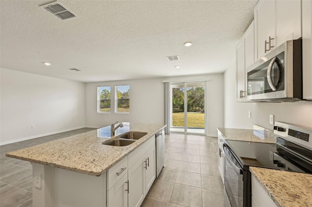 kitchen featuring light stone countertops, stainless steel appliances, a center island with sink, white cabinets, and sink