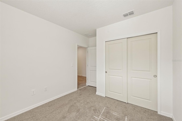 unfurnished bedroom featuring light colored carpet and a closet