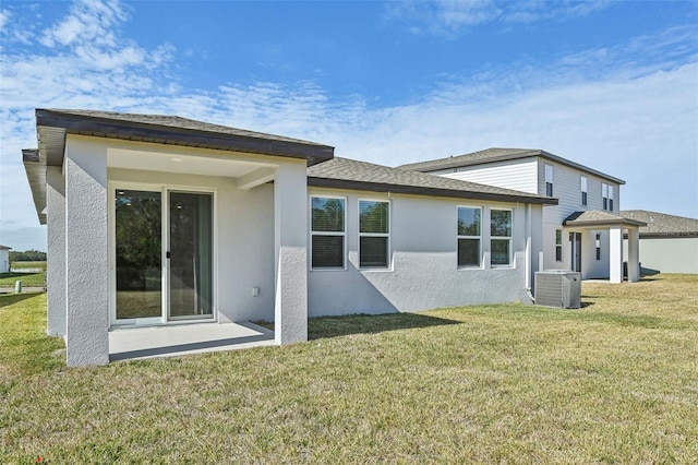 rear view of house with central air condition unit and a lawn