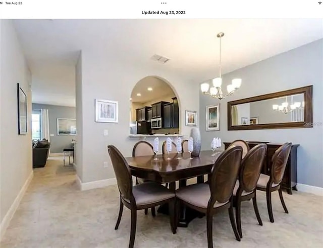 carpeted dining space with an inviting chandelier