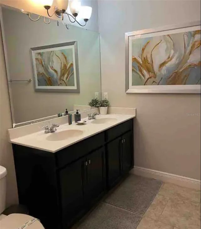 bathroom with toilet, tile patterned flooring, dual bowl vanity, and a chandelier